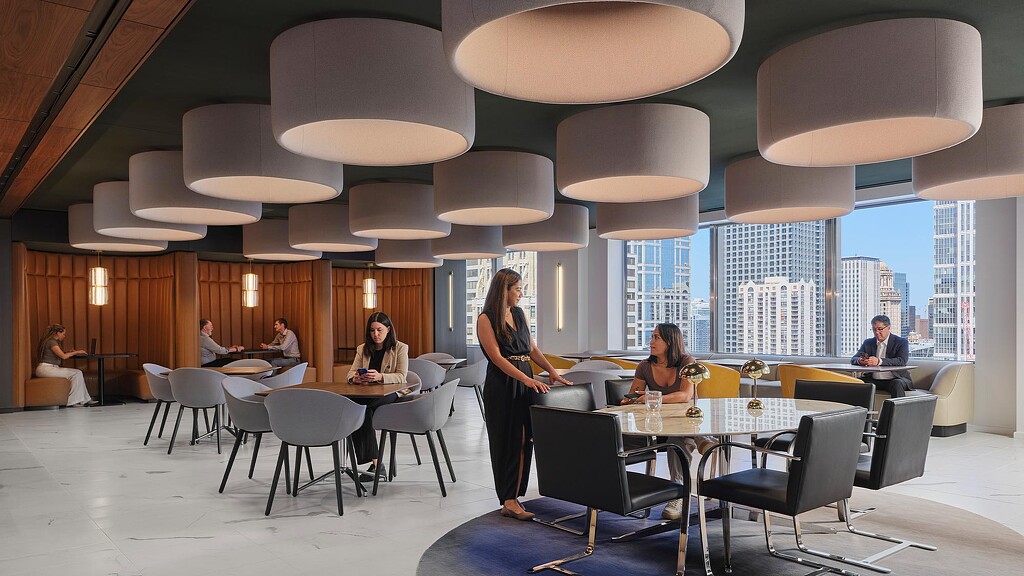 A group of people sitting around a table with a person standing in front of them.