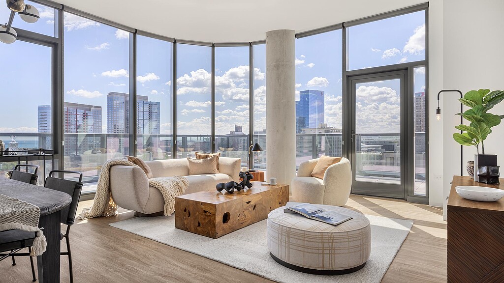 A room with a large window and a couch and a table with a chair and a table with.