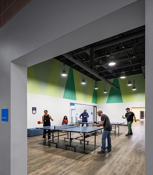 A group of people standing in a room with tables and chairs.