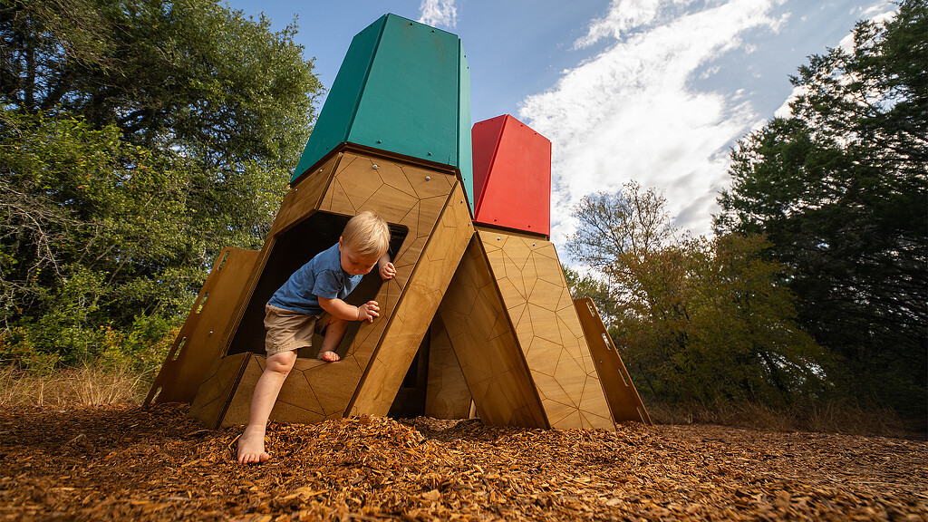 A boy playing in a wooden structure.