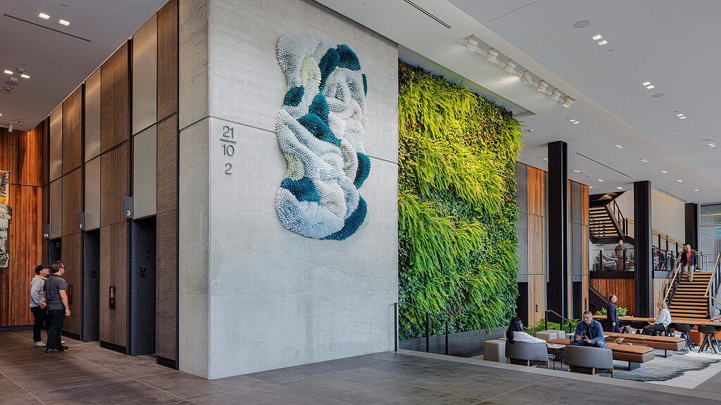 A building with a large tree and a large white wall with a large mural on it.