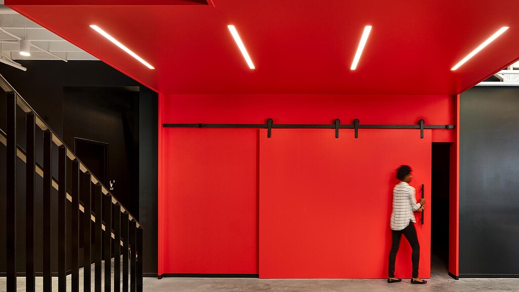 A person standing in front of a red wall.