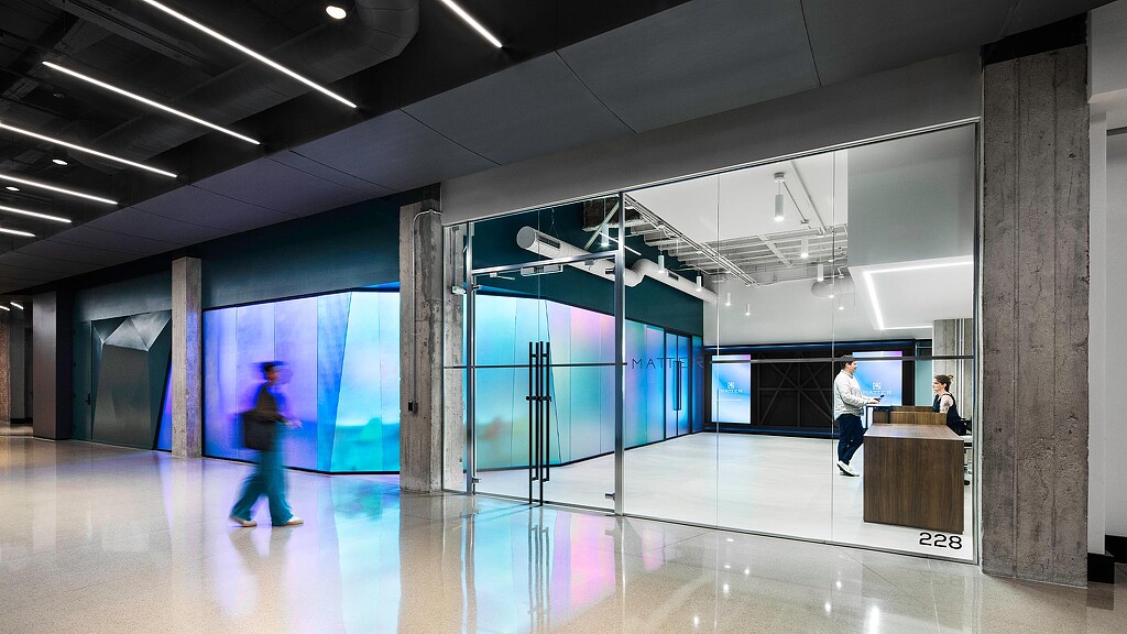 A group of people in a large room with glass walls.