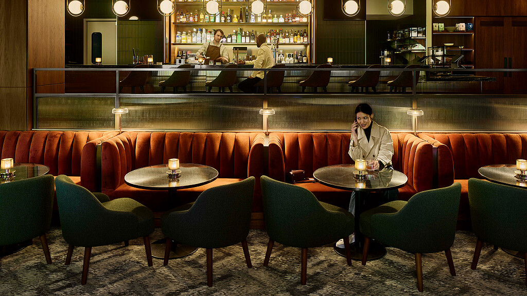 A person standing behind a table with chairs and tables in a restaurant.