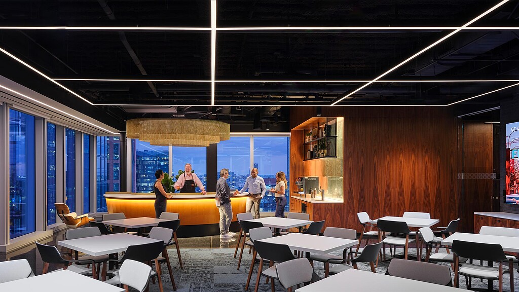 A group of people in a room with tables and chairs.