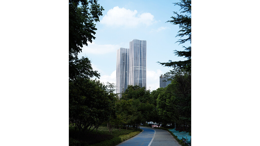 A road with trees and a tall building in the background.