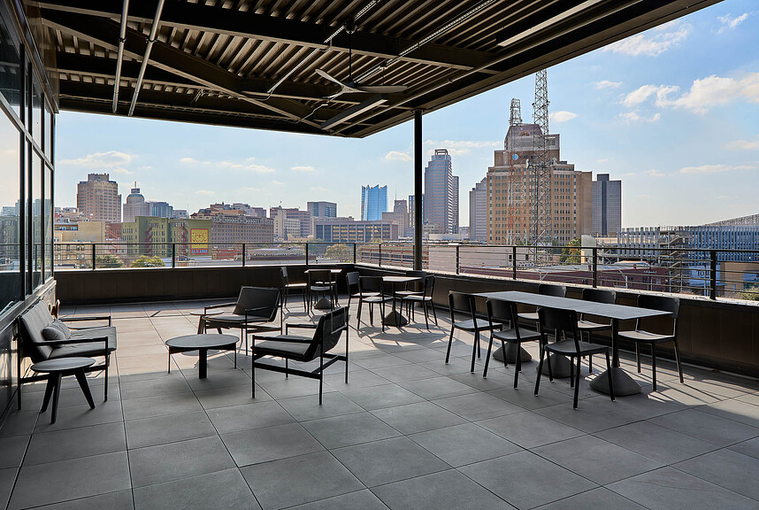A patio with tables and chairs and a city skyline in the background.