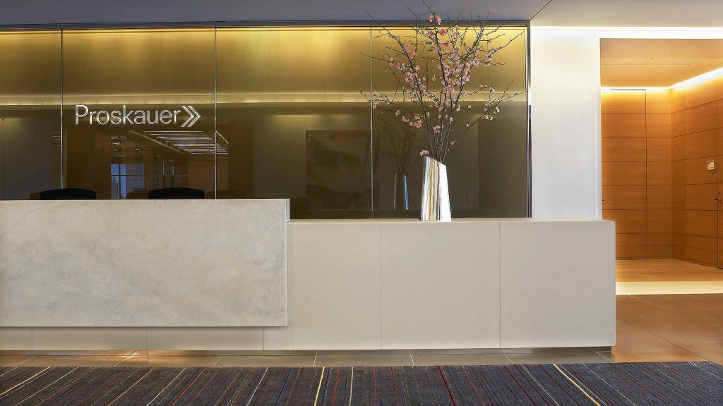A vase with flowers on a white bench in front of a building.
