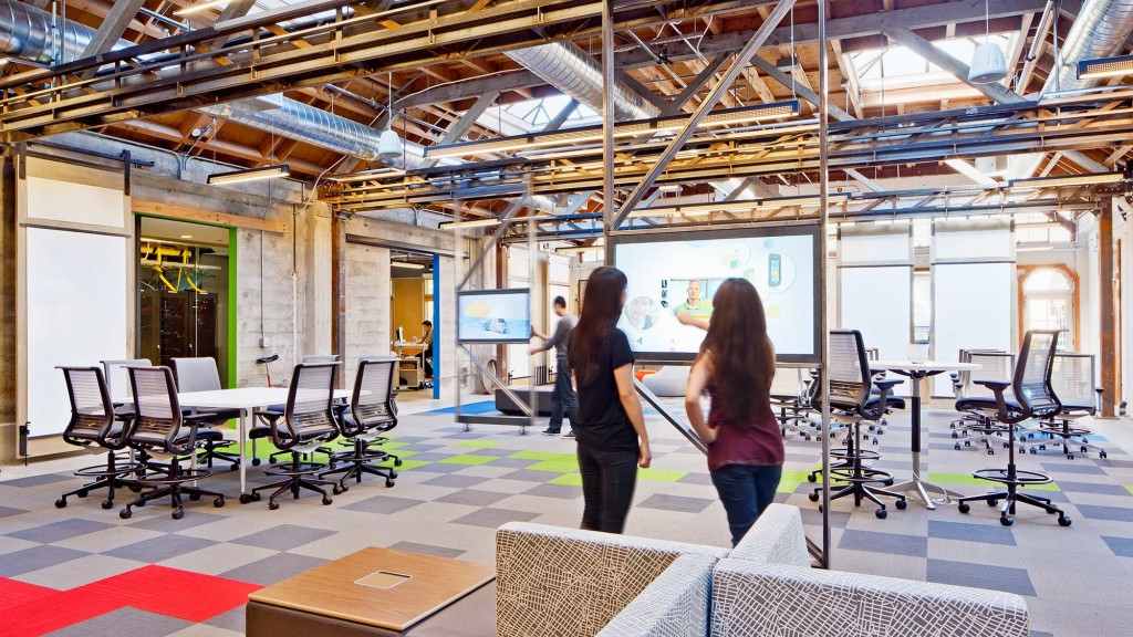 A couple of women in a room with chairs and tables.