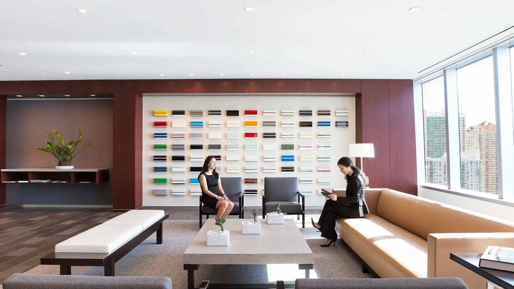 A couple of women sitting in a room with a large window.