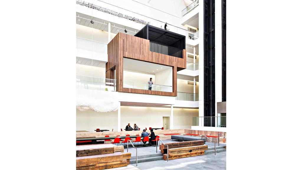 A group of people sitting on a bench in a large building.