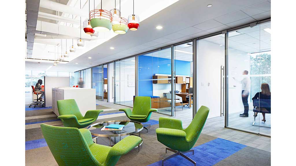 A room with green chairs and a table with a couple people in it.