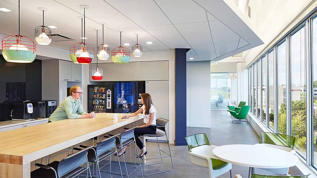 A man and woman sitting at a table in a room with a large window and a large chan.