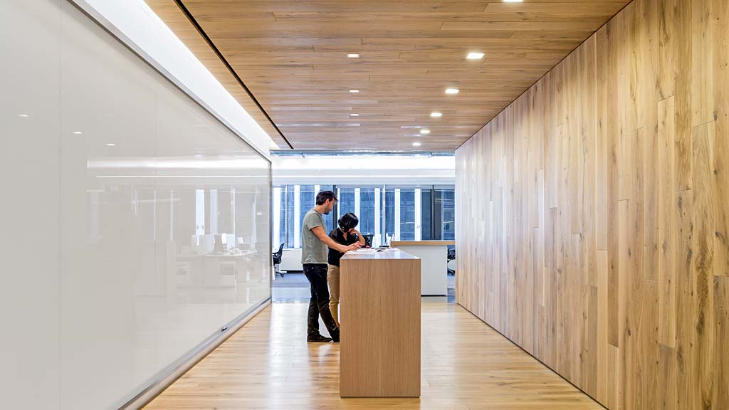 A man and woman hugging in a room with wood floors.
