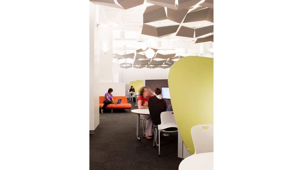 A group of people sitting at a table in a room with a large green lamp.
