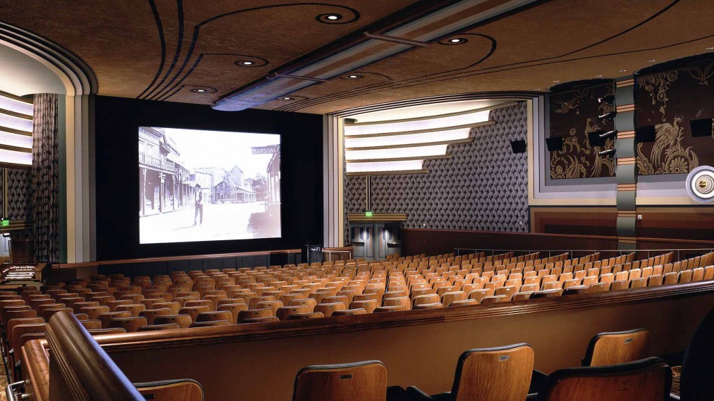 A large room with a large screen and chairs in it.