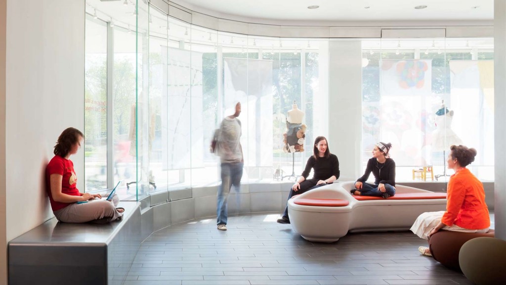A group of people sitting on a couch in a room with large windows.