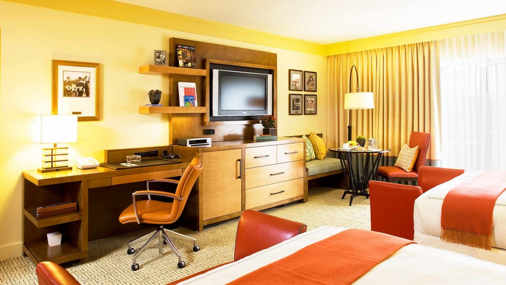 A hotel room with a bed desk and a tv.