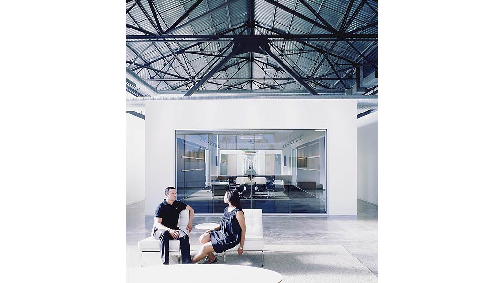 A man and woman sitting on a bench in front of a building.