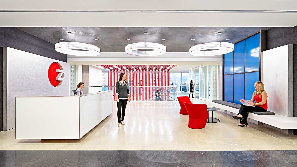 A person standing in a room with a person sitting on a bench.