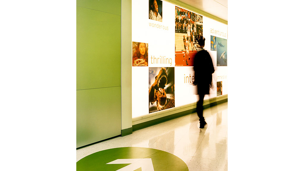 A person walking in a room with posters on the wall.