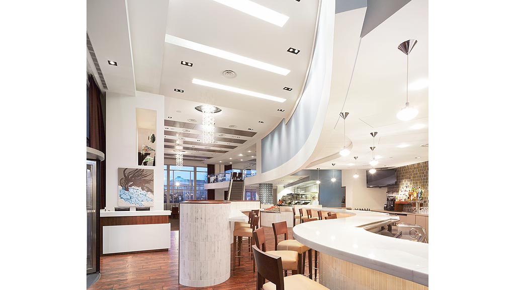 A large kitchen with a bar and chairs.