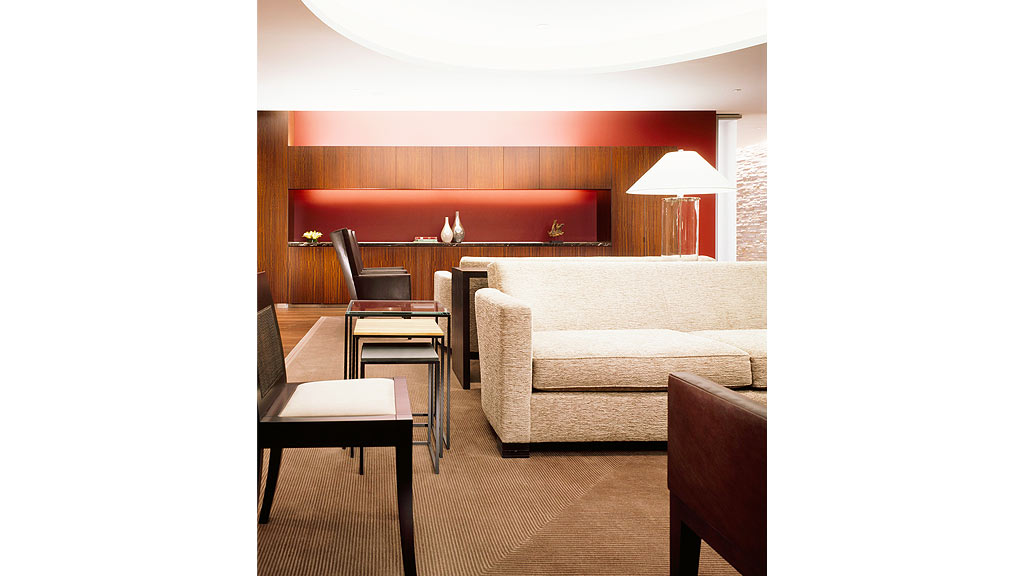 A room with a bed and chairs.