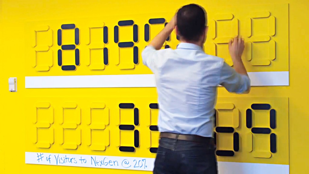 A man standing in front of a yellow wall with black text.
