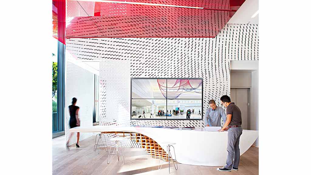 A man and woman looking at a large screen in a room.