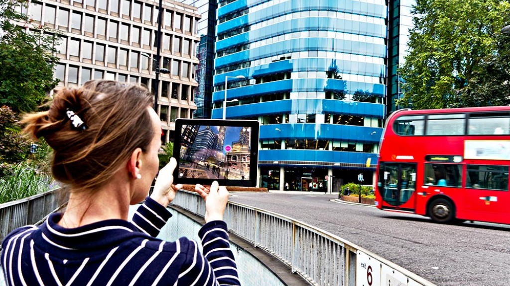 A person holding a picture of a bus and a red bus.