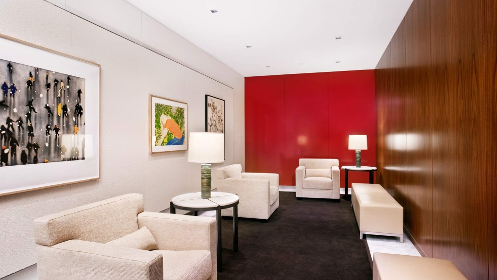 A room with white couches and a table with a lamp on it.