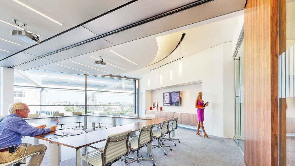 A woman standing in a room with a man sitting at a table.