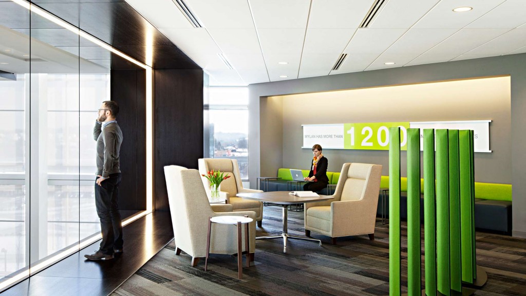 A man standing in a room with a woman sitting at a table.