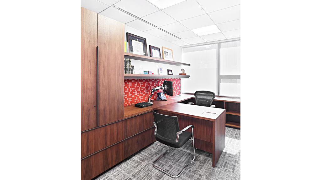 A desk with chairs and a shelf with books on it.