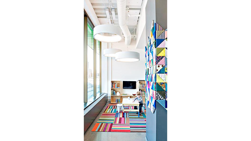 A child sitting at a desk in a room with a television and bookshelves.