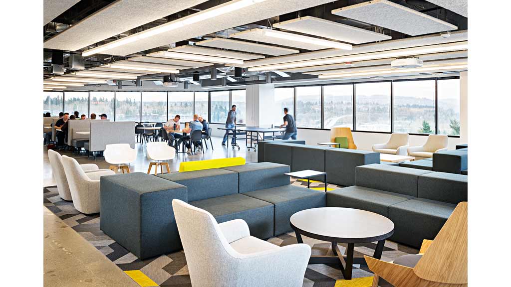A room with a group of people and tables and chairs.