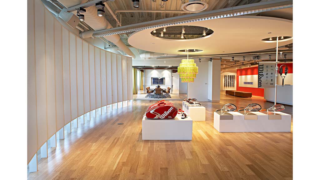 A room with a wood floor and a white table with a red couch.