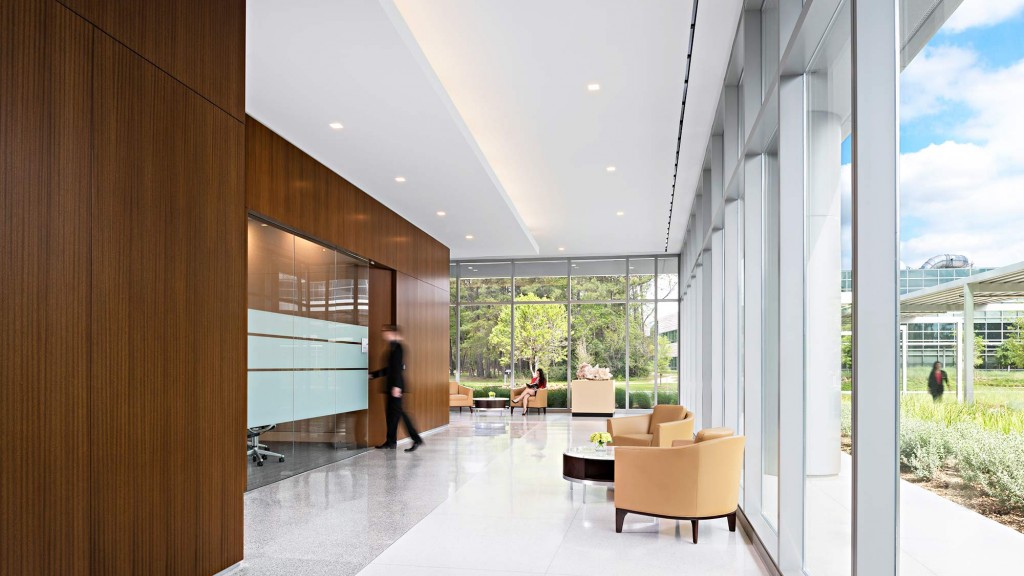 A room with a large glass wall and a person walking in it.