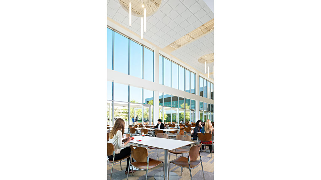 People sitting at tables in a large room with windows.
