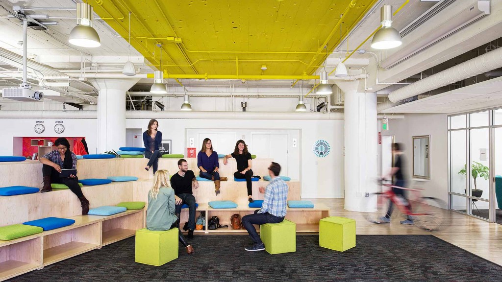 A group of people sitting on benches in a room with a ceiling light.