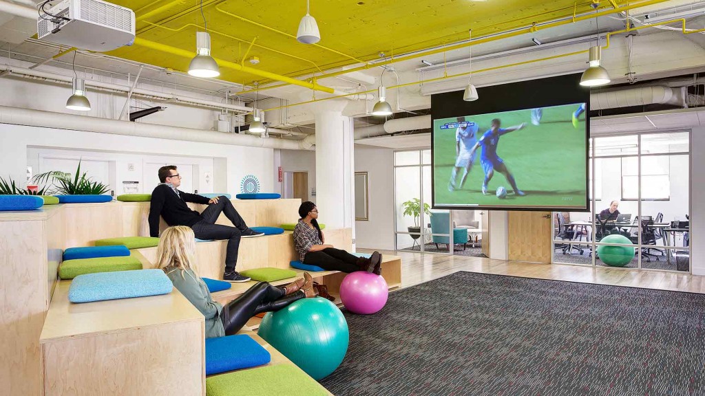 A group of people exercising in a room with a large screen.