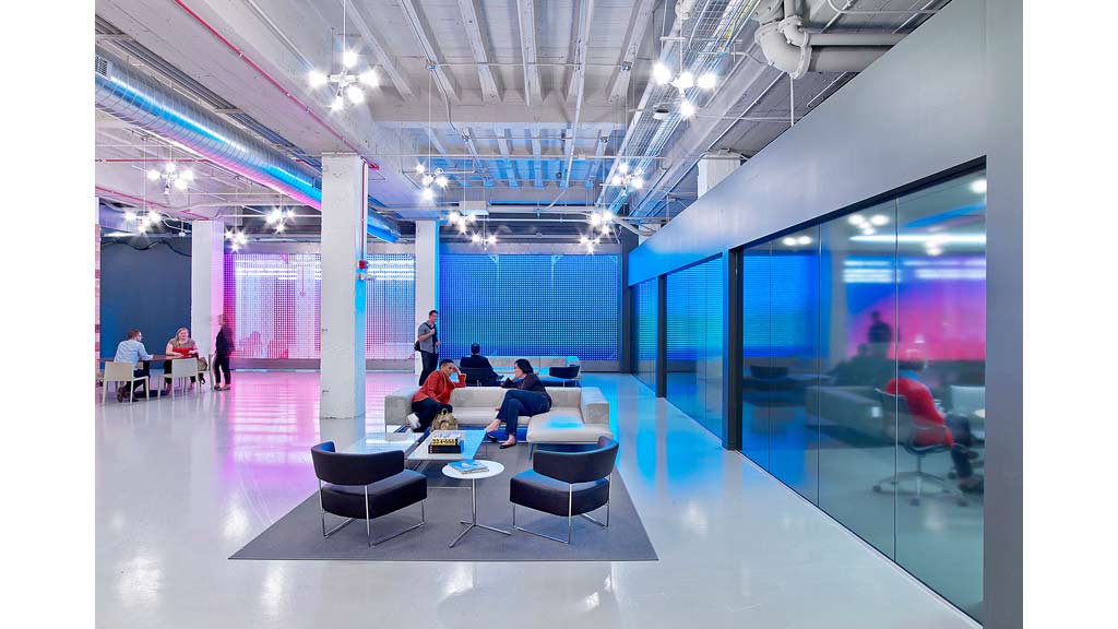 A group of people sitting in a room with blue walls and a large glass floor.