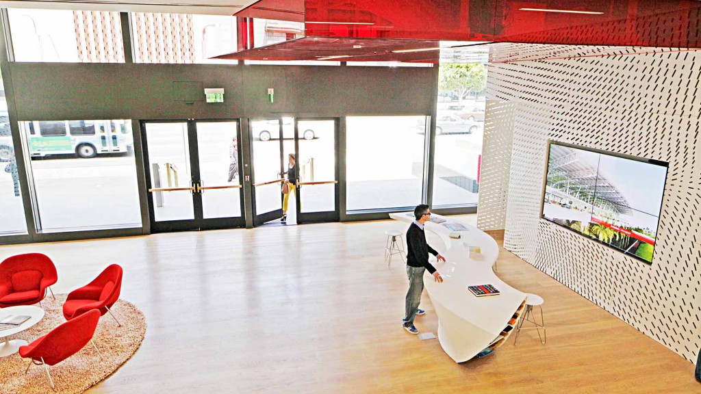 A person standing in a room with a large screen and chairs.