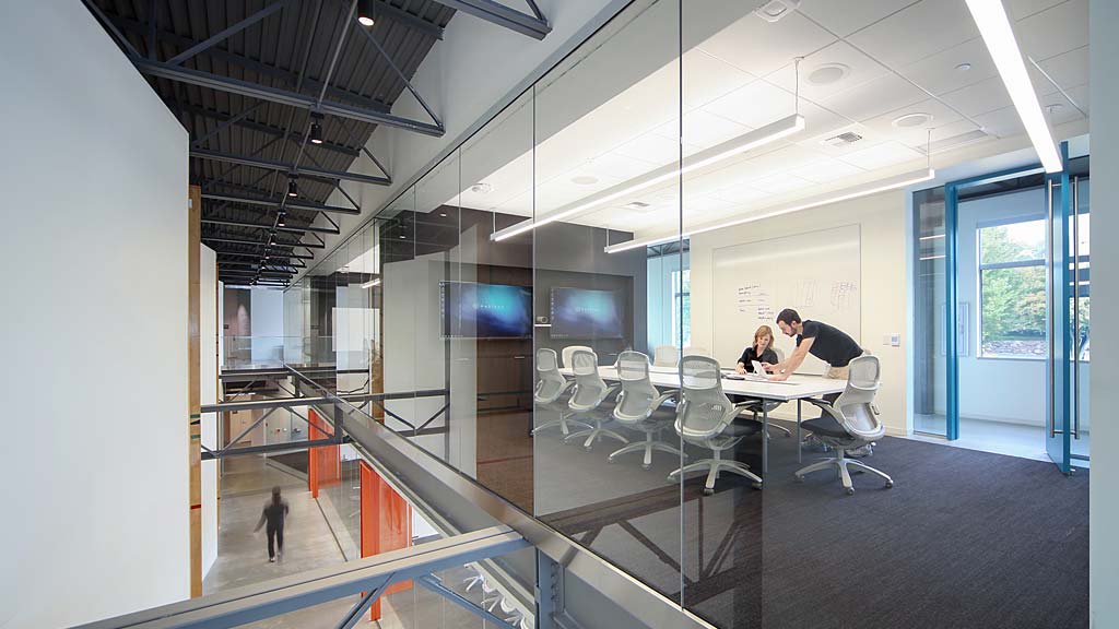 A group of people sitting at a table in a room with glass walls.