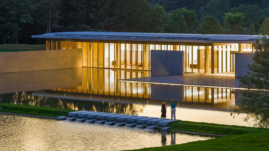 A large building with a pond in front of it.