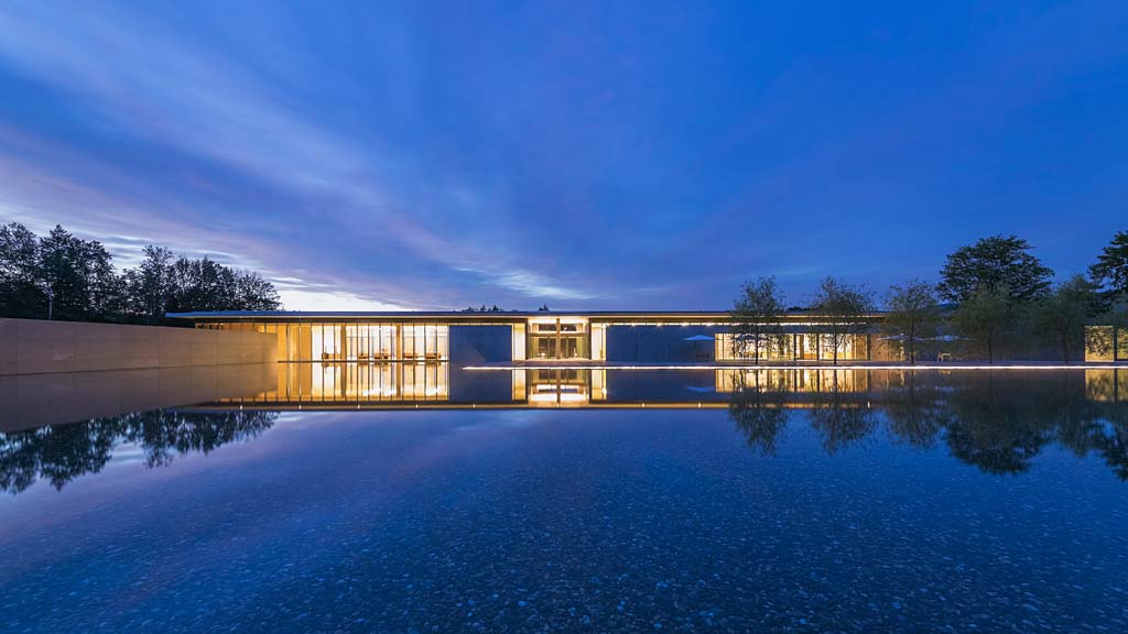 A building with a glass front surrounded by water.