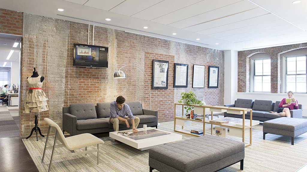 A man and woman sitting on a couch in a living room.