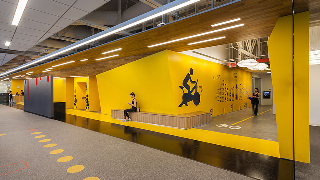 A couple of people in a large building with yellow walls.