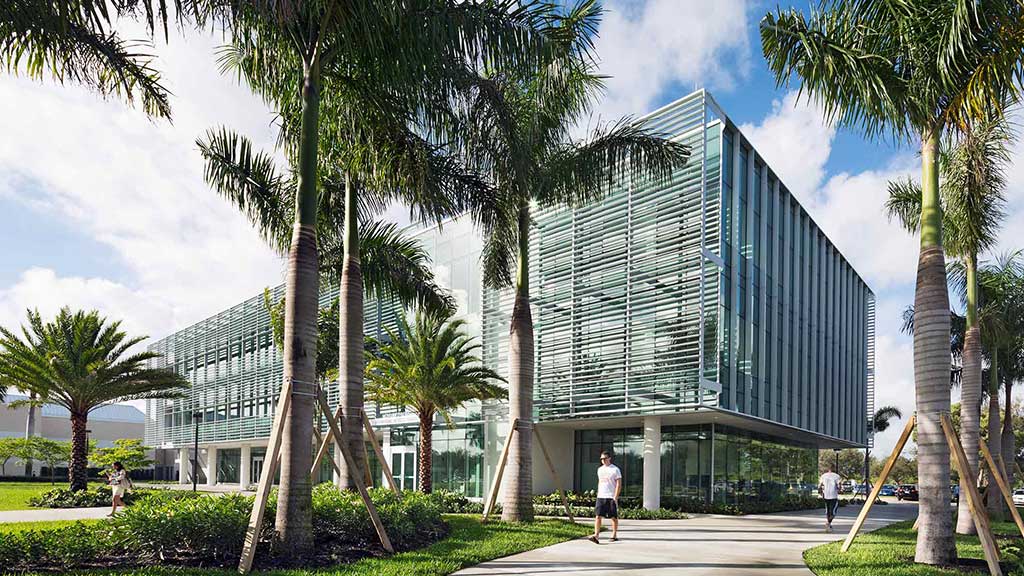A building with palm trees and people walking around.