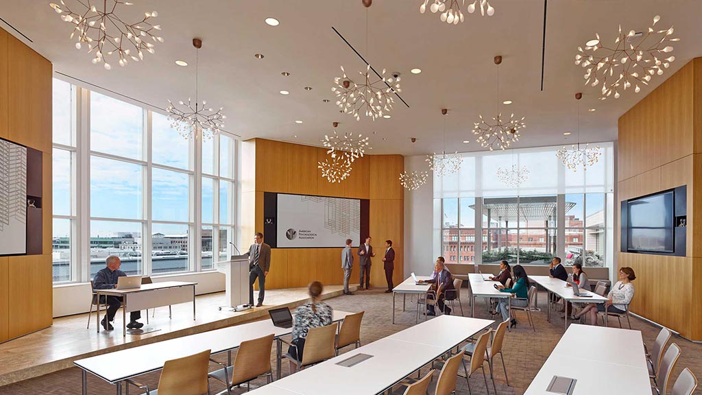 A room with tables and chairs and people in it.